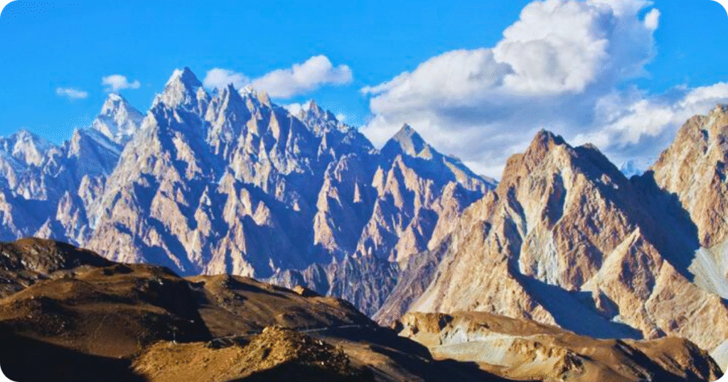 Sharp, pointed peaks of the Passu Cones rising dramatically against a blue sky with scattered clouds.
