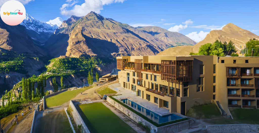 Scenic view of Baltit Heritage Inn, a modern hotel set against the dramatic mountains of Hunza Valley, featuring terraced architecture, green fields, and bright blue skies.