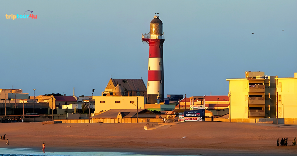 Manora Island lighthouse in Karachi at golden hour, featuring the red-and-white striped tower overlooking the beach and nearby coastal buildings.