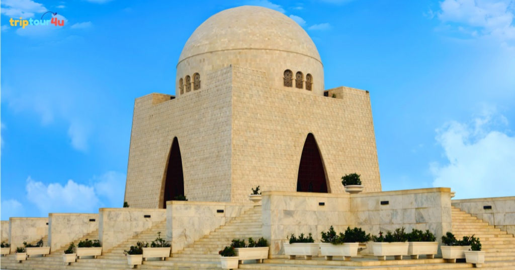 Mazar-e-Quaid in Karachi featuring a white marble mausoleum with a large central dome, geometric arches, and stepped terraces under a bright blue sky.