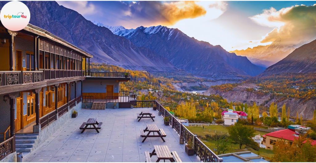 Roomy Khurushal Hunza hotel with a spacious terrace and wooden architecture, overlooking the colorful Hunza Valley and snow-covered mountains at sunset.