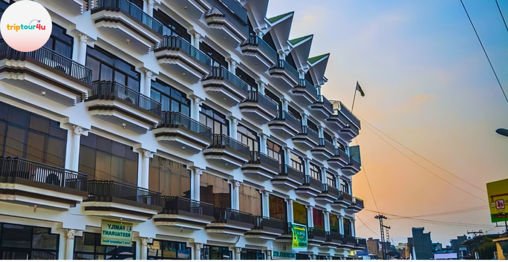 Exterior view of Swat Continental Hotel featuring a multi-story white building with glass windows, multiple balconies, and a cityscape background during sunset.