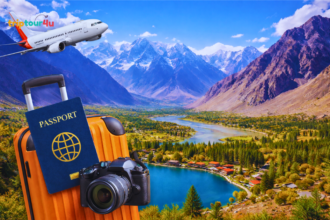 Aerial view of Skardu Valley with Upper Kachura Lake, green forests, snow-capped Karakoram mountains, and subtle travel gear like a backpack, camera, and suitcase.