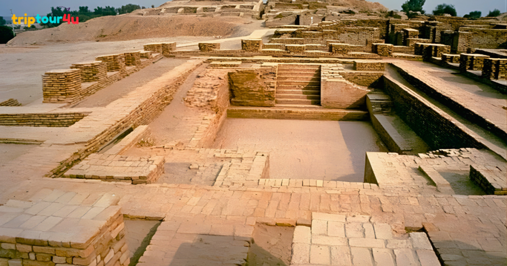 Ancient brick ruins of the Great Bath at Mohenjo-daro, showing a large rectangular sunken pool with stone steps and surrounding platforms in an arid landscape.