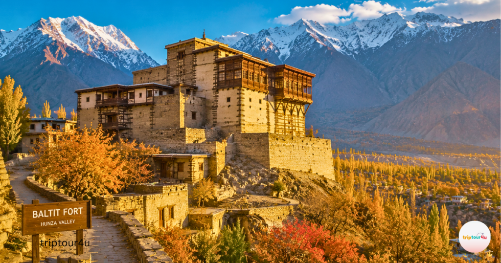 Historic Baltit Fort overlooking Hunza Valley with colorful autumn foliage and majestic snow-covered mountains in Gilgit-Baltistan.