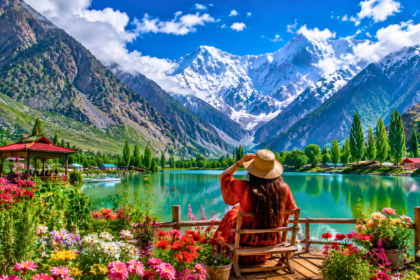Scenic turquoise lake surrounded by colorful flowers, lush valleys, and snow-capped mountains in northern Pakistan